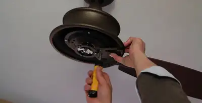 Electrician installing ceiling fan mounting bracket and fixture in Tucson, AZ