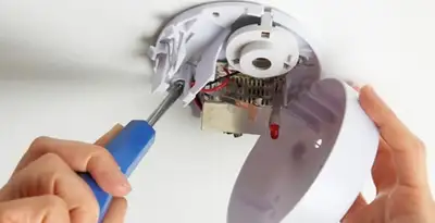 Certified technician wiring smoke detector during installation in Tucson, AZ